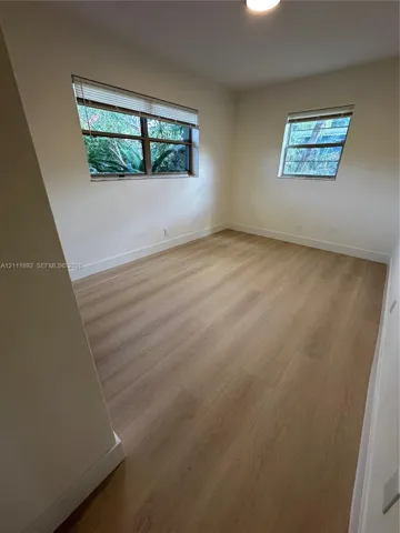 Neutral wall tones, wood-finish flooring, and multiple windows with integrated blinds