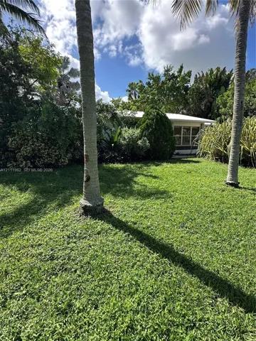 Expansive lawn featuring mature palm trees and established tropical landscaping
