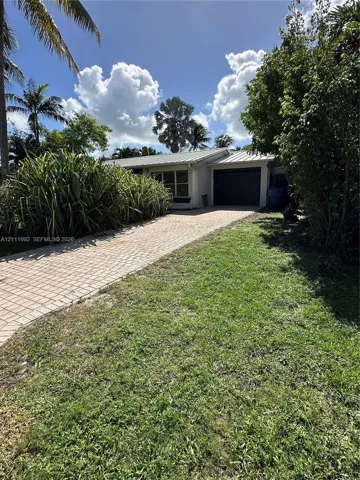Single-story exterior featuring a metal roof, paver driveway, and attached garage