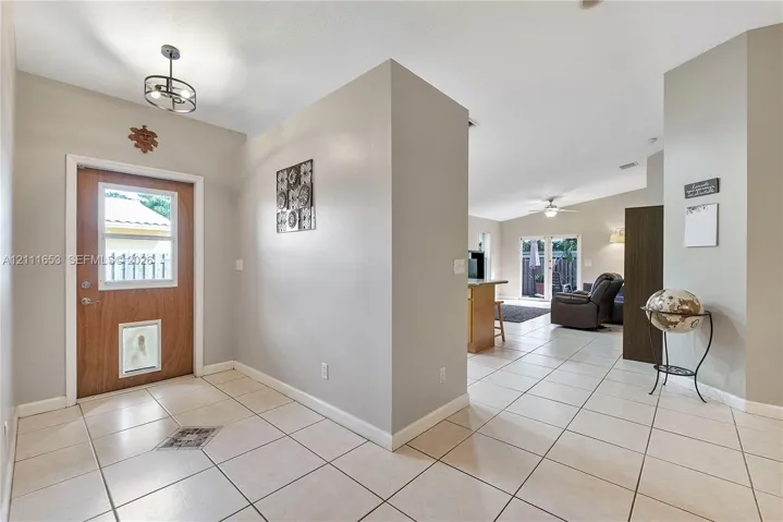 Entryway featuring tile flooring, neutral wall paint, and a wood-finish exterior door with a glass inset
