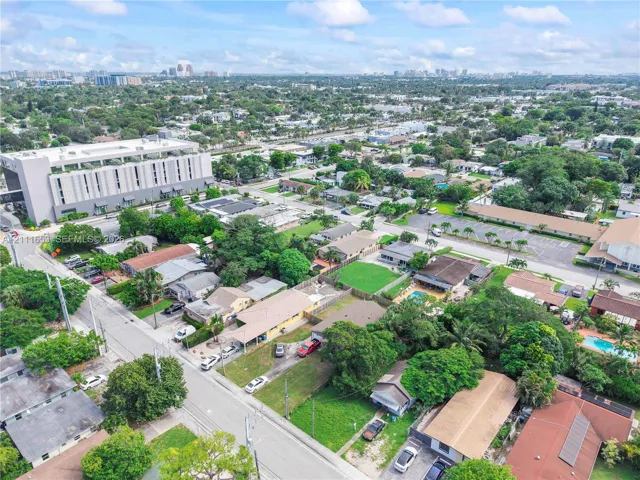 Aerial perspective featuring established residential surroundings with mature trees, expansive green lawns, and diverse roofline configurations