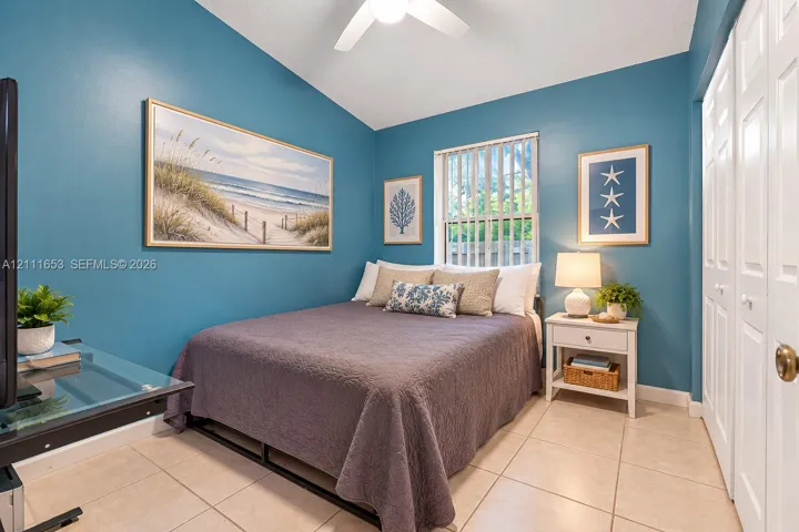 Bedroom 2 vaulted ceiling, ceramic tile flooring, vertical window blinds, and dual-panel closet doors
