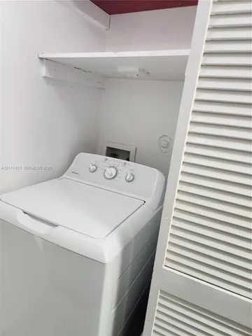 Laundry area featuring a built-in overhead storage shelf and louvered closet doors