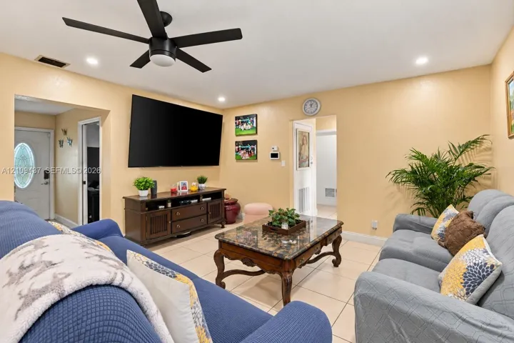 Living area featuring large-format tile flooring, matte black ceiling fan, and recessed lighting