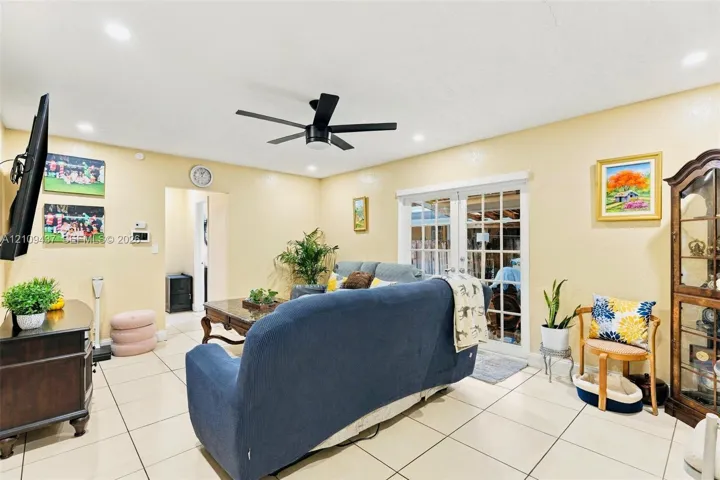 Interior space featuring large-format ceramic tile flooring, recessed ceiling lighting, a matte black multi-blade ceiling fan, and sliding glass doors with paneled inserts