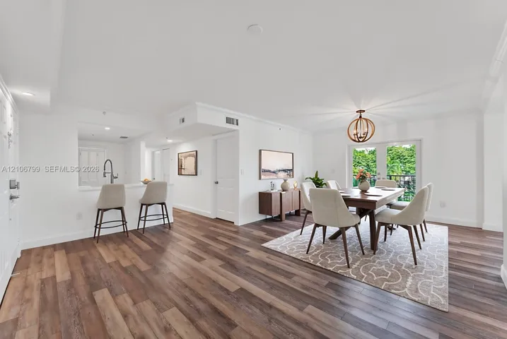 Open-concept area featuring wood-finish flooring, a kitchen pass-through counter with an attached faucet, and glass-paneled double doors