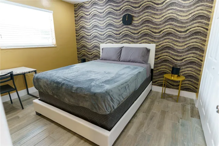 Room featuring patterned wall covering, wood-finish tile flooring, and a multi-panel door
