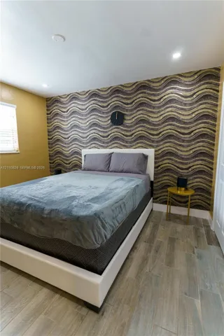 Room featuring wood-finish tile flooring, recessed ceiling lighting, and a textured, wave-patterned accent wall