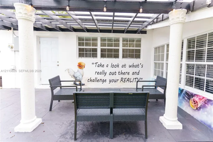 Patio area featuring a dark-toned pergola, decorative columns, and multi-pane windows