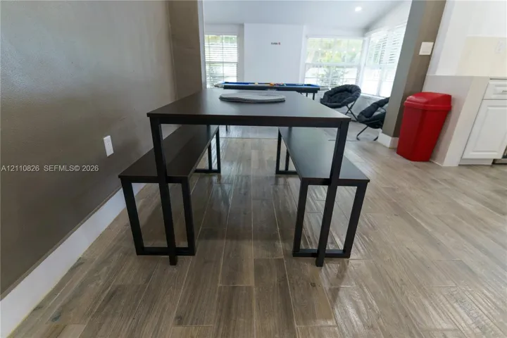 Wood-finish flooring throughout, white cabinetry, and large windows with horizontal blinds