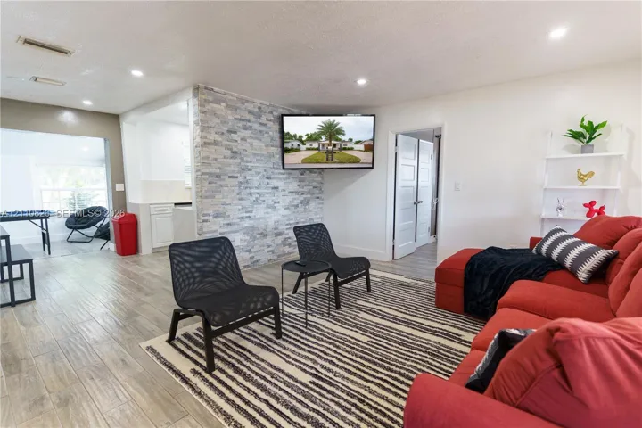 Living area featuring wood-finish flooring, a stacked stone accent wall, and recessed lighting