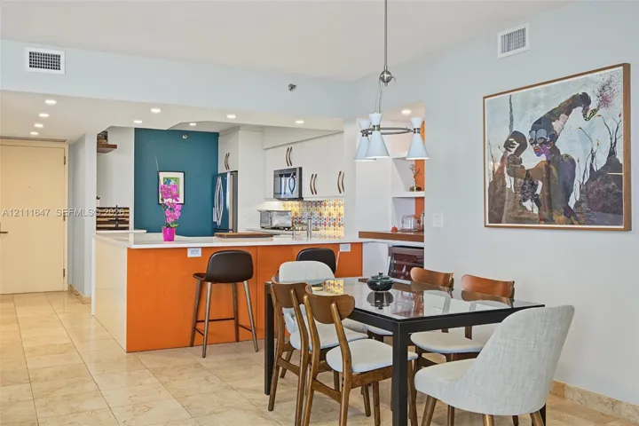 Kitchen featuring white cabinetry, island with integrated seating, patterned tile backsplash, recessed lighting, and tile flooring