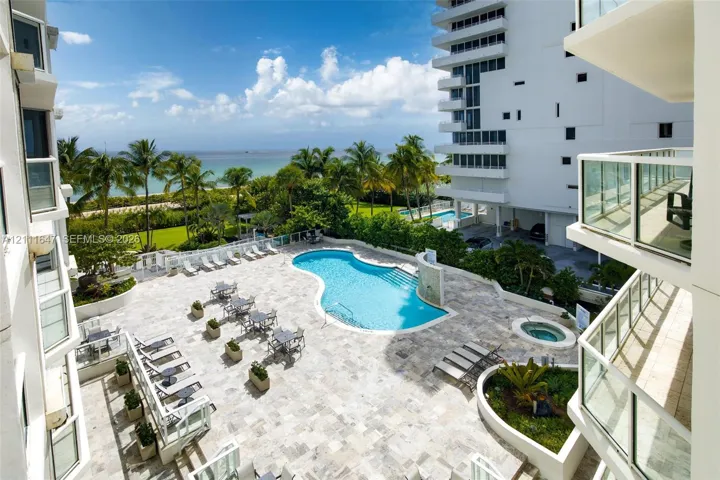 Swimming pool with tiered entry, integrated spa, paved sun deck, and ocean horizon