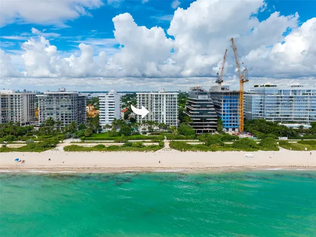 High-rise building situated on an oceanfront lot featuring direct beach access, coastal scenery, and mature landscaping