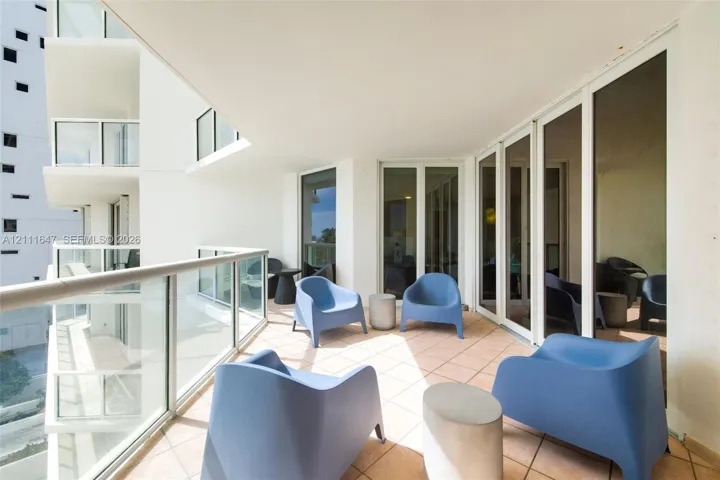 Covered balcony featuring tile flooring, glass panel railing, and multi-panel glass sliding doors