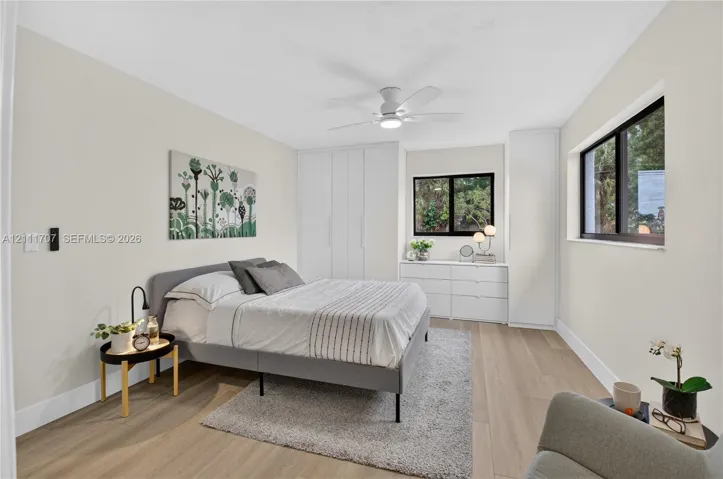 Room featuring wood-finish flooring, built-in floor-to-ceiling cabinetry, dual windows with black frames, and a ceiling-mounted light fixture