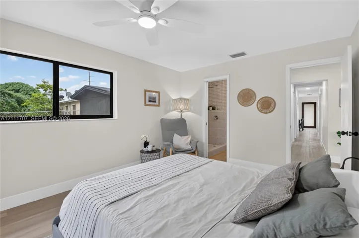 Neutral-toned interior featuring wood-finish flooring, a contemporary ceiling fan with integrated lighting, and large, black-framed picture windows