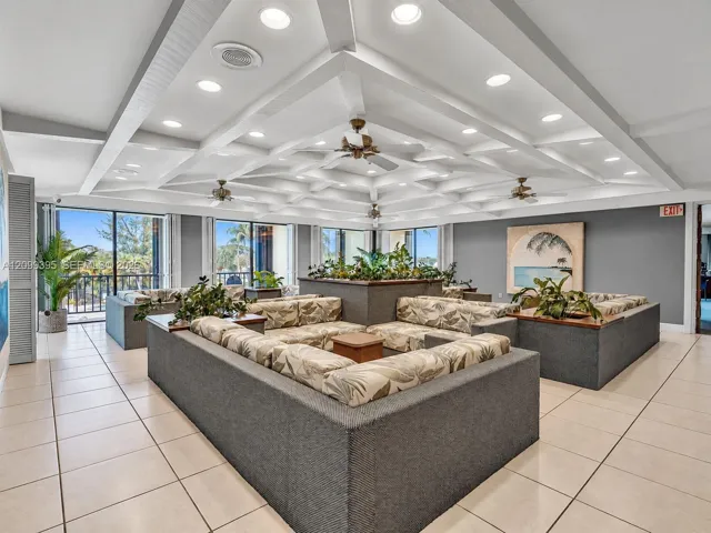 Expansive common area featuring a coffered ceiling, recessed lighting, ceiling fans, tile flooring, and large glass sliding doors