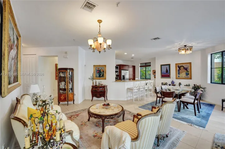 Open-concept interior featuring light-toned tile flooring, recessed lighting, and dual multi-arm chandeliers