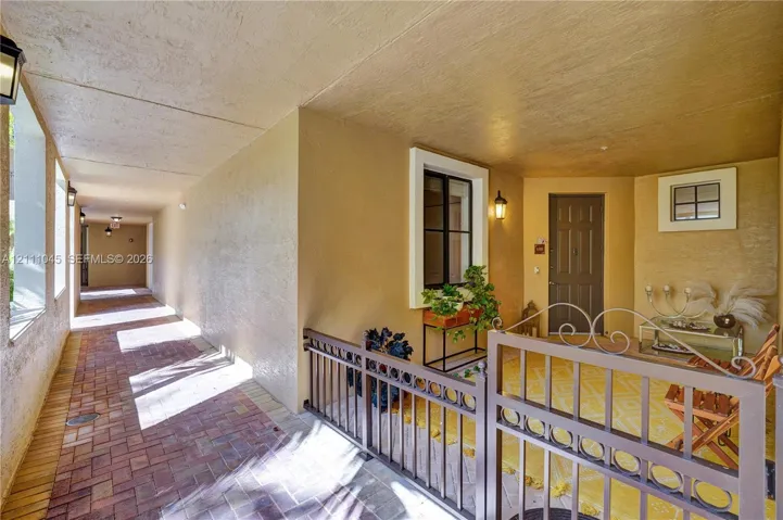 Covered entryway featuring brick pavers, decorative metal fencing, recessed lighting, and a paneled entry door