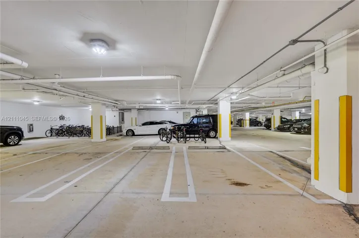 Covered parking garage featuring concrete flooring, designated stalls with painted line markings, structural columns, and integrated bicycle racks