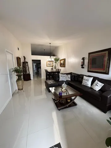 Open-concept interior featuring large-format tile flooring, vaulted ceilings, and a hanging pendant light fixture