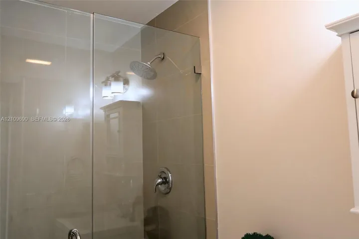 Bathroom 1 Walk-in shower featuring a glass enclosure, large-format tile wall surround, rainfall showerhead, and single-handle chrome fixture