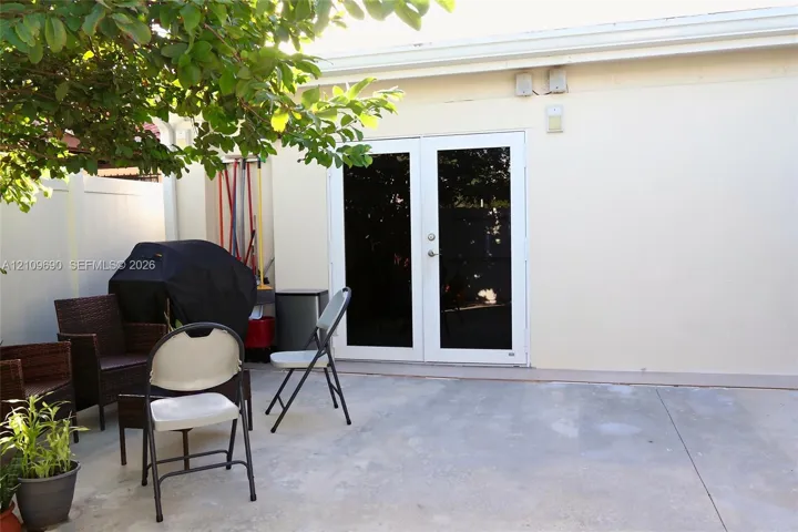 Concrete patio featuring white vinyl perimeter fencing and double glass-paned doors