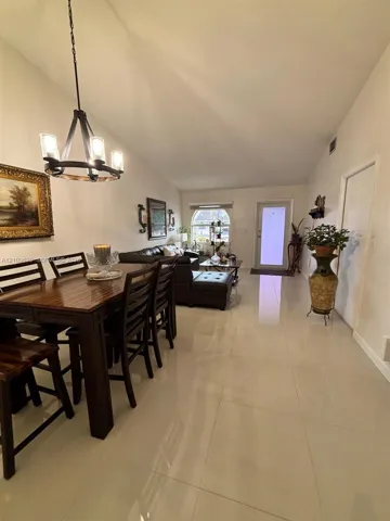 Vaulted ceilings, large-format tile flooring, arched window, and a rustic iron chandelier