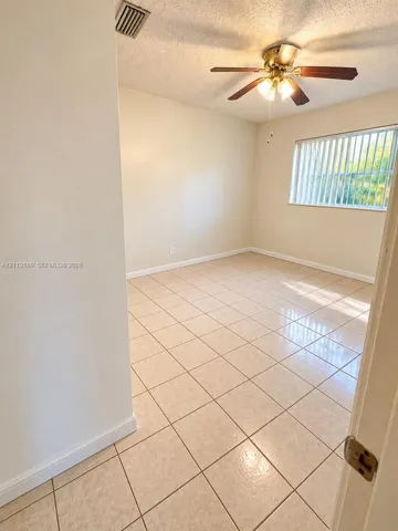Neutral-toned tile flooring, multi-blade ceiling fan with integrated light fixture, and horizontal window blinds