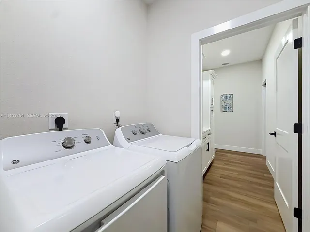 Laundry room featuring wood-finish flooring, white cabinetry, and recessed lighting
