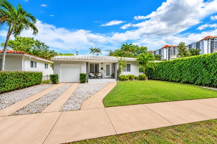 Single-story residence featuring a barrel tile roof, concrete driveway, attached garage, and manicured lawn