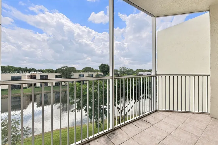 Screened-in balcony featuring tile flooring and metal railing overlooking a water feature