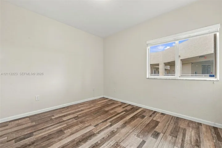 Neutral-toned interior featuring wood-finish flooring and a single-pane window with white blinds