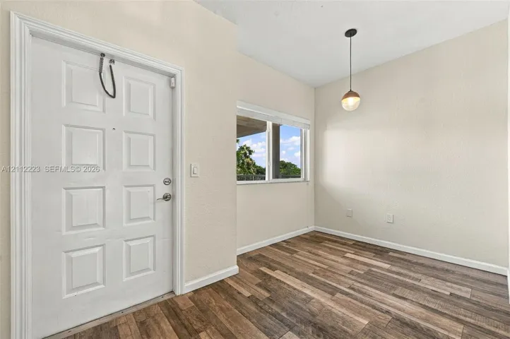 Entry area featuring a six-panel door, wood-finish flooring, a pendant light fixture, and a window with a neutral finish
