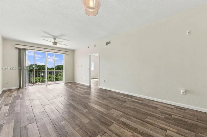Wood-finish flooring, glass sliding door, ceiling fan with light fixture, pendant lighting, and neutral wall paint
