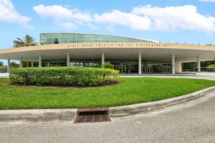 Circular structure featuring a curved glass facade, an expansive covered overhang, and structural support columns