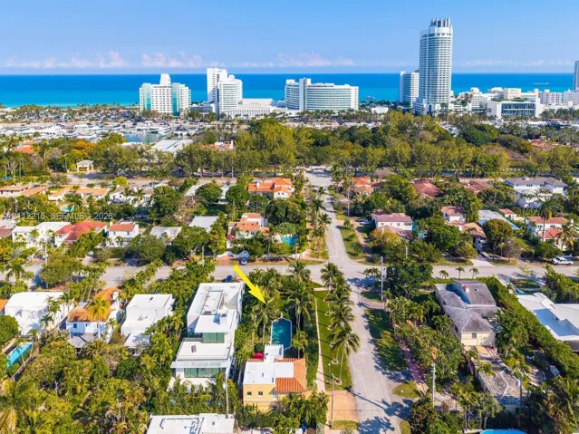 Aerial perspective featuring a multi-story residence with a red-tile roof and a private in-ground swimming pool surrounded by mature palm trees