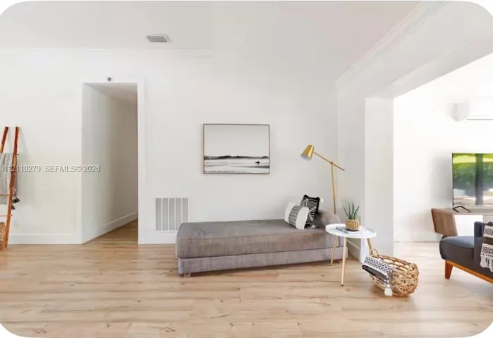 Light-toned wood-finish flooring, crisp white walls, and decorative crown molding
