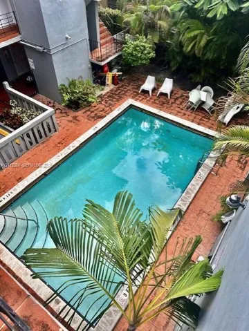 In-ground swimming pool featuring tiered stairs, stone coping, and a surrounding clay-tile patio deck