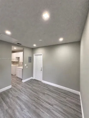 Neutral-toned interior featuring wood-finish flooring, recessed lighting, and a six-panel door