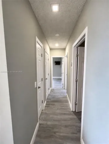 Interior hallway featuring wood-finish flooring, recessed lighting, and multiple interior paneled doors