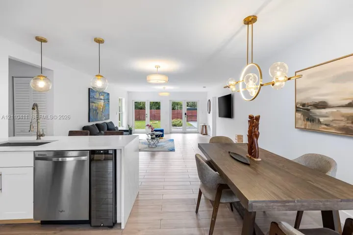 Kitchen featuring quartz countertops, stainless steel dishwasher, and built-in wine refrigerator, complemented by wood-finish flooring and designer pendant lighting
