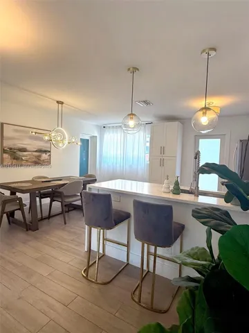Kitchen featuring a central island with a solid surface countertop, white shaker-style cabinetry, wood-finish flooring, and globe-style pendant lighting