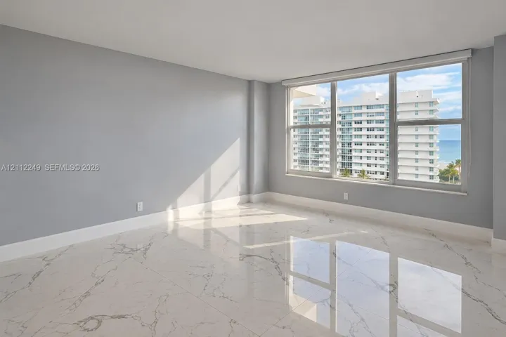 Large-format polished stone flooring with veining detail, expansive windows, and neutral interior paint palette