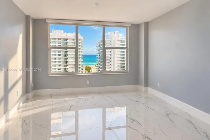 Large-format window featuring ocean and coastal scenery, finished with polished stone-look tile flooring and neutral wall paint
