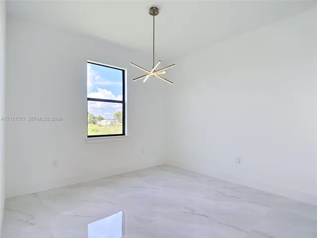 Modern room featuring stone-finish tile flooring, a multi-arm linear chandelier, and a single-hung window with a black frame
