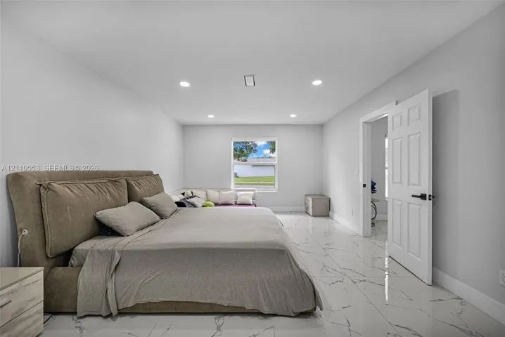 Interior room featuring large-format tile flooring with veining, recessed lighting, and a multi-panel door with matte black hardware