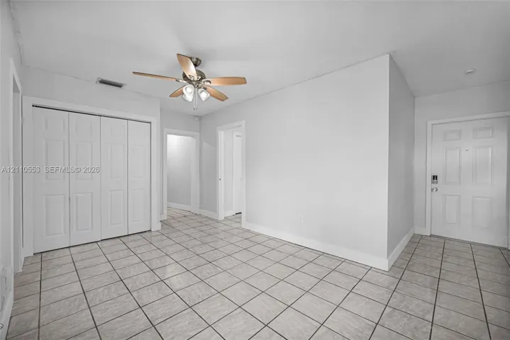 Interior space featuring neutral wall paint, grid-pattern tile flooring, a multi-panel door, built-in closet with multi-panel doors, and a ceiling-mounted light fixture with a fan