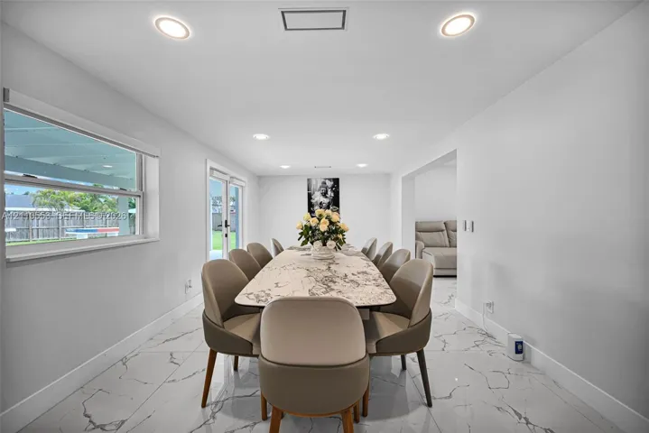 Large-format stone-look flooring, recessed ceiling lighting, and glass paneled doors providing exterior access